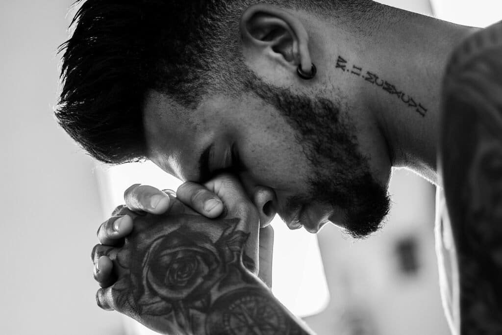 What Is Christianity? 6 Man with tatoos praying to Jesus