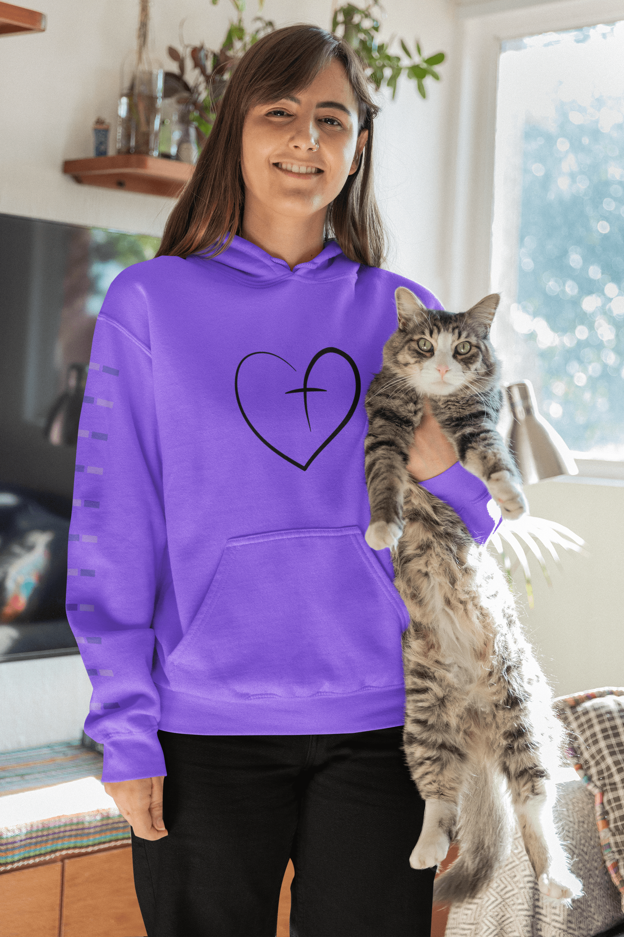 Brunette-woman-wearing-a-purple-hoodie-with-a-cross-and-heart-symbol-while-holding-a-gray-cat