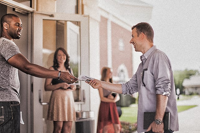 Church-group-standing-outside-of-a-church-building-shaking-hands-and-smiling-at-one-another