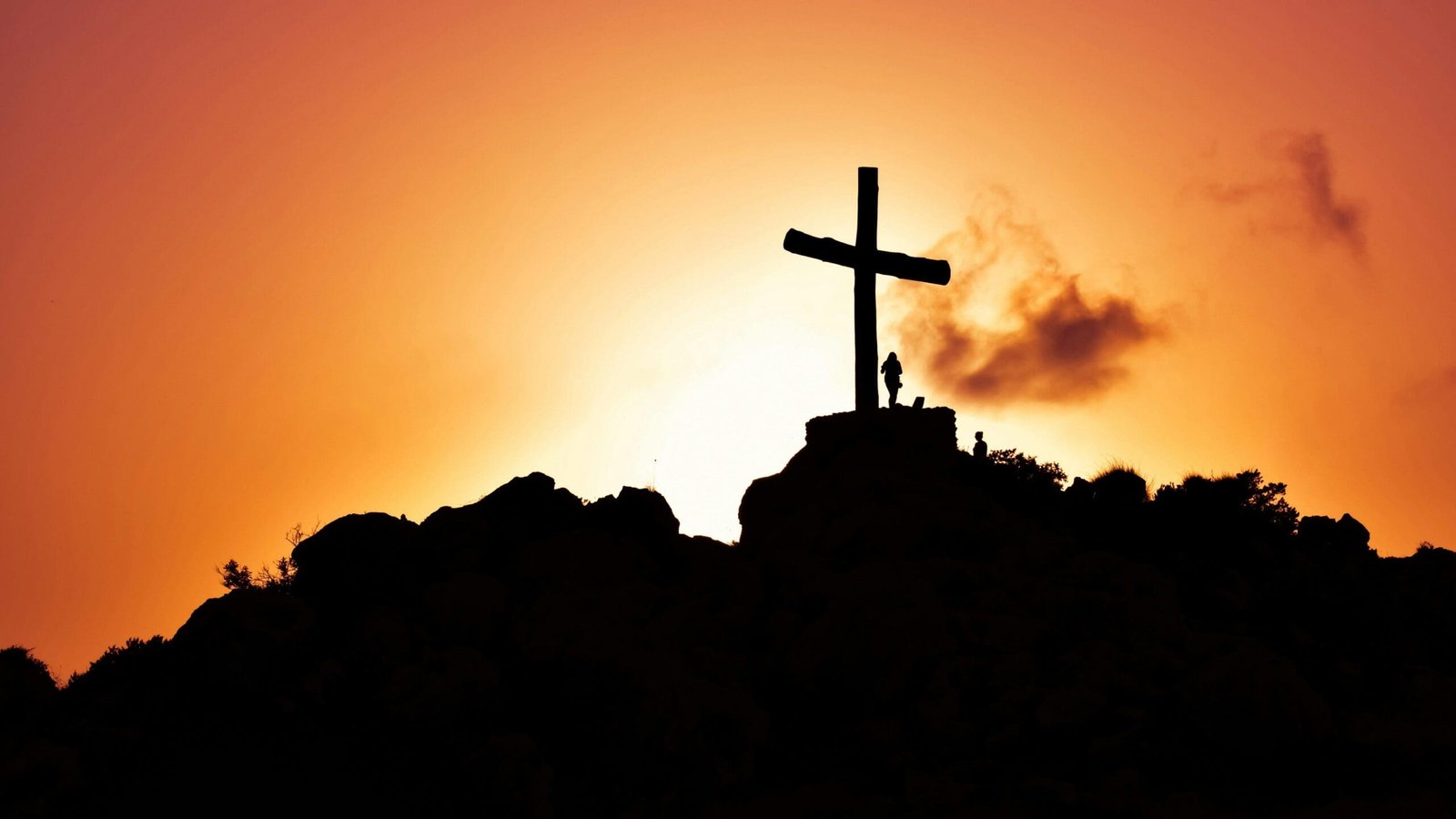 a silhouette of a cross on a hill